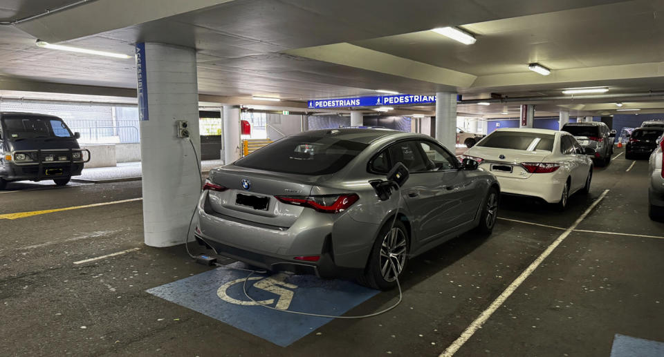 Electric vehicle parked in commercial car park charging via smart point. 