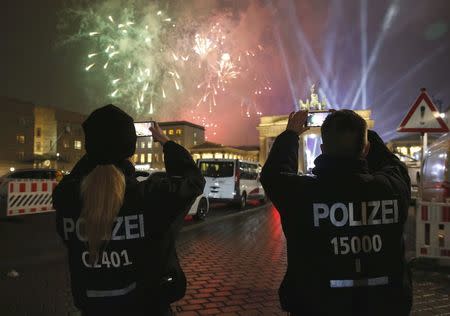 German police officers take pictures as fireworks explode next to the Quadriga sculpture atop the Brandenburg gate during New Year celebrations in Berlin, Germany, January 1, 2017. REUTERS/Fabrizio Bensch