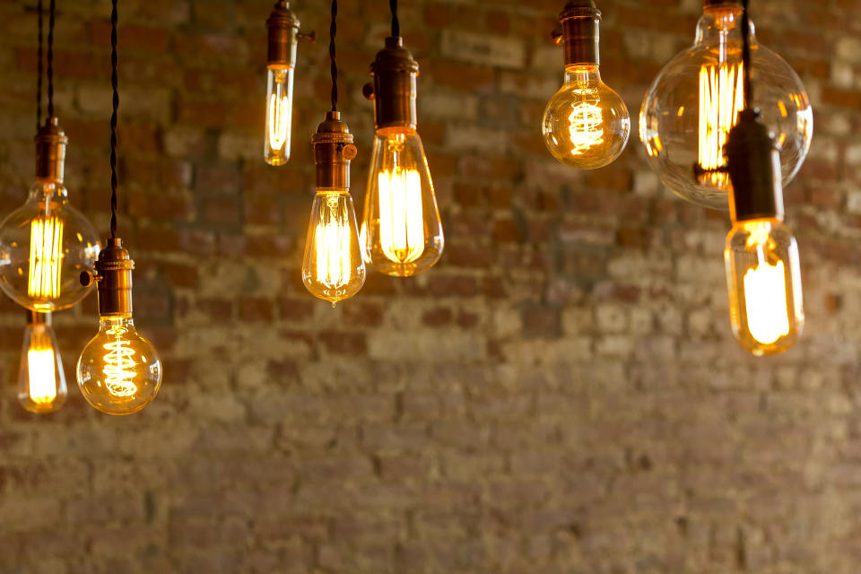 Hanging vintage-style light bulbs with glowing filaments in front of a textured brick wall