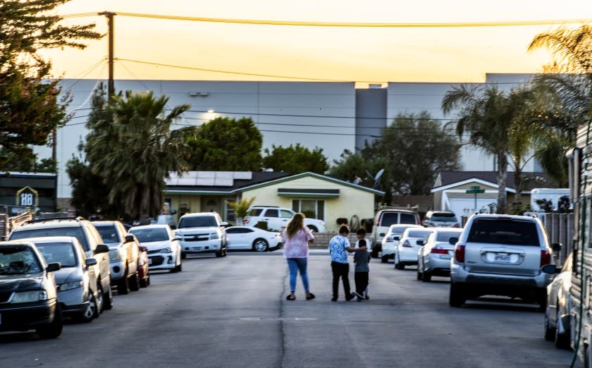 JURUPA VALLEY, CA - APRIL 30, 2021: A family walks in their neighborhood which is surrounded on two sides by giant warehouses off Etiwanda Avenue on April 30, 2021 in Jurupa Valley, California. The increase in warehouses in the Inland Empire has also increased the diesel truck traffic causing more air pollution in the Southland.(Gina Ferazzi / Los Angeles Times)