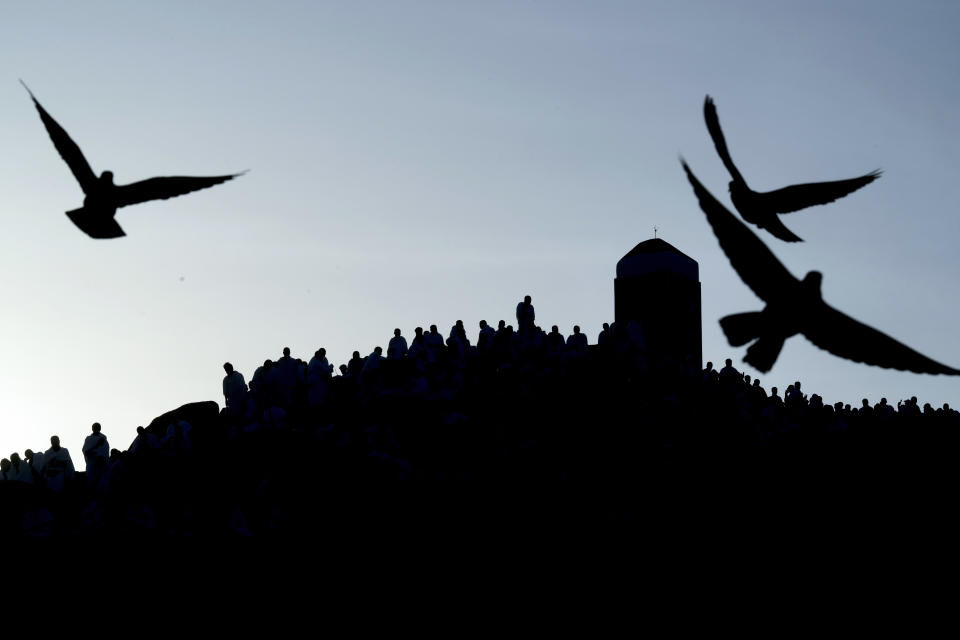Pigeons fly as Muslim pilgrims pray on top of the rocky hill known as the Mountain of Mercy, on the Plain of Arafat, during the annual hajj pilgrimage, near the holy city of Mecca, Saudi Arabia, Friday, July 8, 2022. One million pilgrims from across the globe amassed on Thursday in the holy city of Mecca in Saudi Arabia to perform the initial rites of the hajj, marking the largest Islamic pilgrimage since the coronavirus pandemic upended the annual event — a key pillar of Islam. (AP Photo/Amr Nabil)
