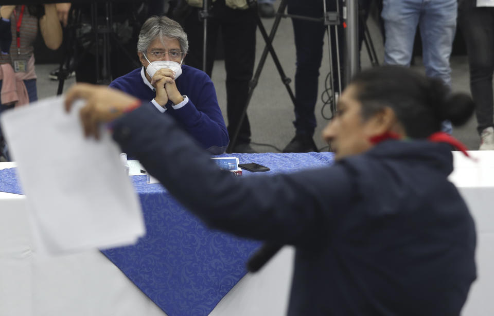 Presidential candidate Guillermo Lasso, representing the Creating Opportunities party or CREO, sitting across from rival Yaku Perez, with the Pachakutik political party, attends an event outside the National Electoral Committee office in which they are both asking for a ballot recount of Sunday's election, in Quito, Ecuador, Friday, Feb. 12, 2021. It remains undecided which of the two has the votes to advance to the run-off race in April to face frontrunner Andres Arauz. (AP Photo/Dolores Ochoa)