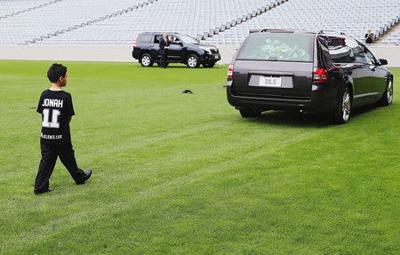 The son of former All Black player Jonah Lomu, Dhyreille Lomu, walks behind the hearse containing his father's casket as it leaves a memorial service at Eden Park in Auckland, New Zealand November 30, 2015. REUTERS/Hannah Peters/Pool