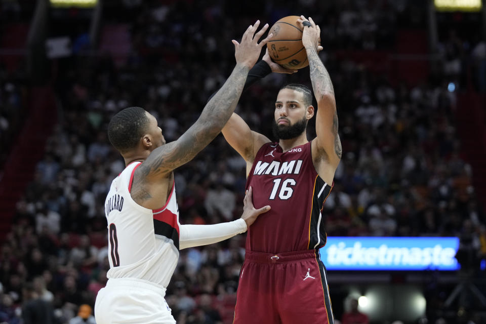 Miami Heat forward Caleb Martin (16) looks for an open teammate past Portland Trail Blazers guard Damian Lillard (0) during the second half of an NBA basketball game, Monday, Nov. 7, 2022, in Miami. (AP Photo/Wilfredo Lee)