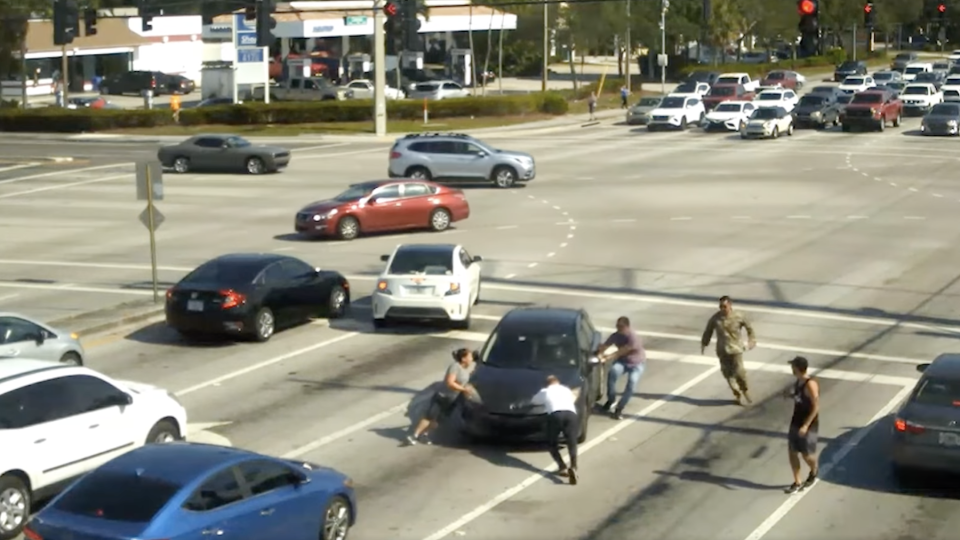 Several people working to stop the woman's car.