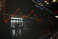 An employee of the Stock Exchange is reflected in a chart displaying stock prices in Athens.