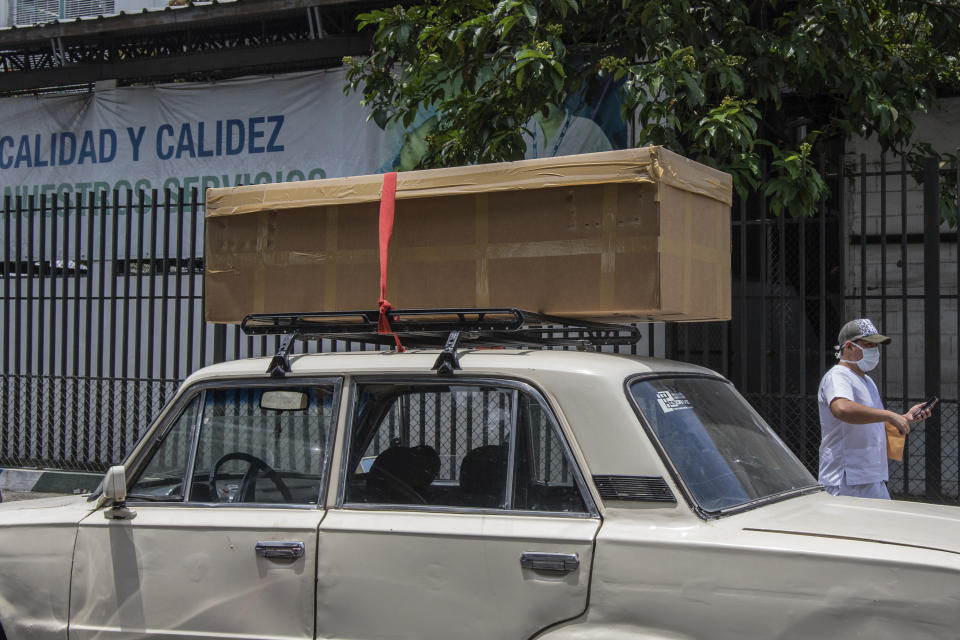 A cardboard coffin with a body sits on the roof rack of a car before it is taken away to be buried, outside the Teodoro Maldonado Hospital in Guayaquil, Ecuador, Monday, April 6, 2020. Guayaquil, a normally bustling city that has become a hot spot in Latin America as the coronavirus pandemic spreads, also has untold numbers dying of unrelated diseases that can’t be treated because hospitals are overwhelmed. (AP Photo/Luis Perez)