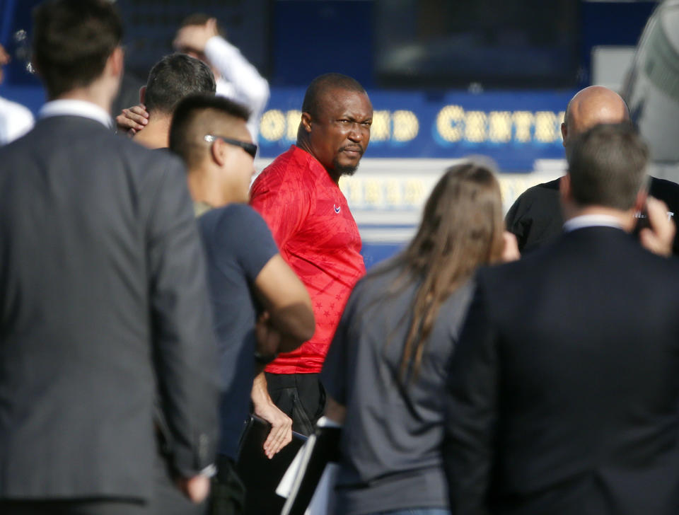 Federal agents hold a detainee, center, at a downtown Los Angeles parking lot after predawn raids that saw dozens of people arrested in the L.A. area Thursday, Aug. 22, 2019. U.S. authorities have unsealed a 252-count federal grand jury indictment charging 80 people with participating in a conspiracy to steal millions of dollars through a range of fraud schemes and laundering the funds through a Los Angeles-based network. The U.S. Attorney's Office says Thursday most of the defendants are Nigerian nationals. (AP Photo/Reed Saxon)