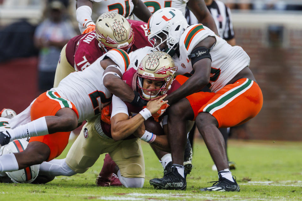 Florida State quarterback Jordan Travis, center bottom, pushes through Miami defenders for a first down during the first half of an NCAA college football game, Saturday, Nov. 11, 2023, in Tallahassee, Fla. (AP Photo/Colin Hackley)