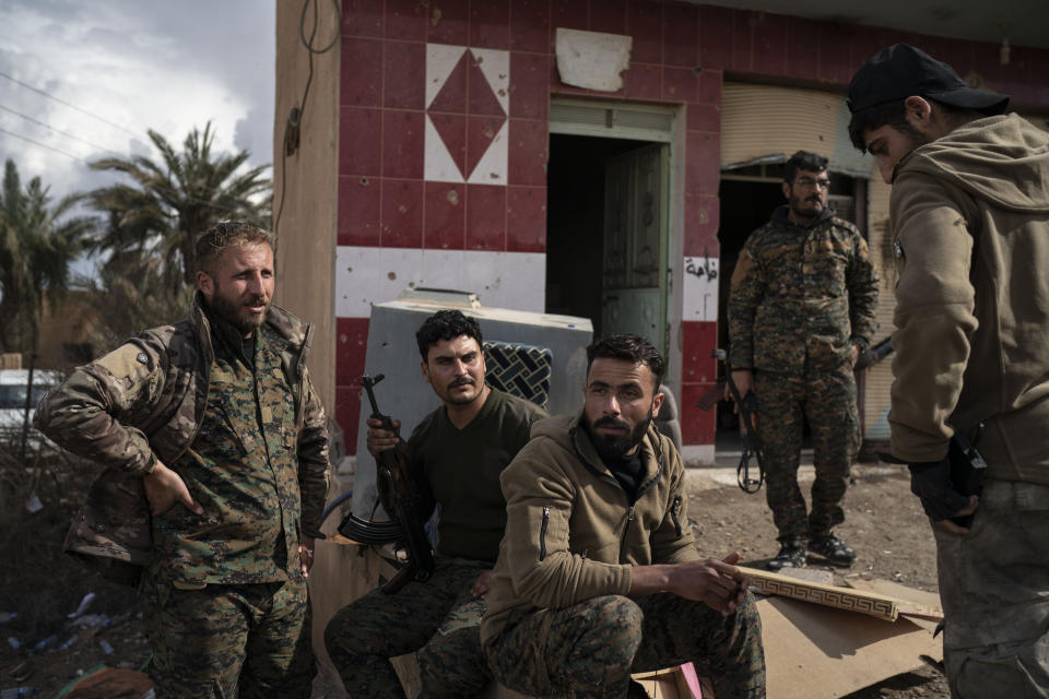 U.S.-backed Syrian Democratic Forces (SDF) fighters stand outside a building used as a temporary base near the last land still held by Islamic State militants in Baghouz, Syria, Monday, Feb. 18, 2019. Hundreds of Islamic State militants are surrounded in a tiny area in eastern Syria are refusing to surrender and are trying to negotiate an exit, Syrian activists and a person close to the negotiations said Monday. (AP Photo/Felipe Dana)