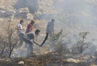 Jewish settlers fight fire in olive groves near their outpost that was caused by Israeli police's teargas canisters, used to disperse Palestinian farmers going to their groves, in the West Bank village of Burqa, East of Ramallah, Friday, Oct. 16, 2020. Palestinians clashed with Israeli border police in the West Bank on Friday during their attempt to reach and harvest their olive groves near a Jewish settlers outpost. (AP Photo/Nasser Nasser)