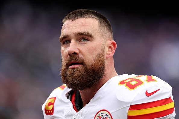 Travis Kelce in a football uniform with a 'C' captain patch, looking up