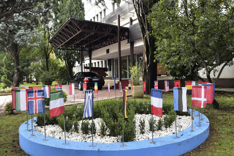 In this photo taken Monday, Nov. 11, 2019, the NATO flag, center, and flags of member countries wave in front of the Montenegrin Defense Ministry in Podgorica, Montenegro. Deployed inside the sprawling communist-era army command headquarters in Montenegro’s capital, a group of elite U.S. military cyber experts are plotting strategy in a fight against potential Russian and other cyberattacks ahead of the 2020 American and Montenegrin elections. (AP Photo/Risto Bozovic)