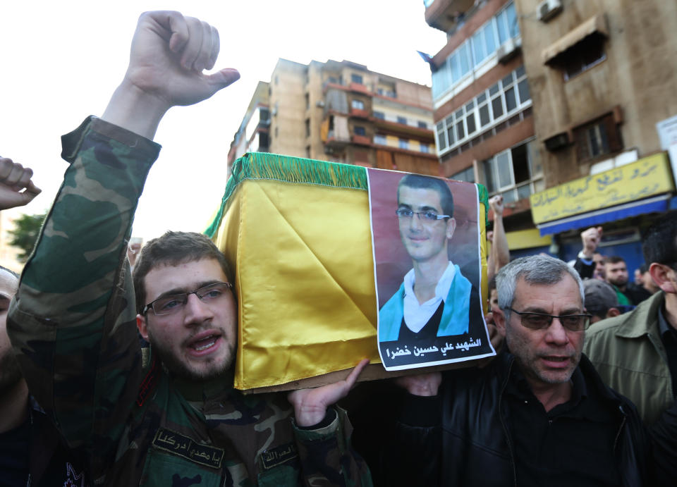 The father, right, and brother of Ali Khadra, left, who was killed Thursday by a bomb explosion, carry his coffin during his funeral procession in the southern suburb of Beirut, Lebanon, Saturday, Jan. 4, 2014. An explosion tore through a crowded commercial street Thursday in a south Beirut neighborhood that is bastion of support for the Shiite group Hezbollah, killing several people, setting cars ablaze and sending a column of black smoke above the Beirut skyline. (AP Photo/Hussein Malla)