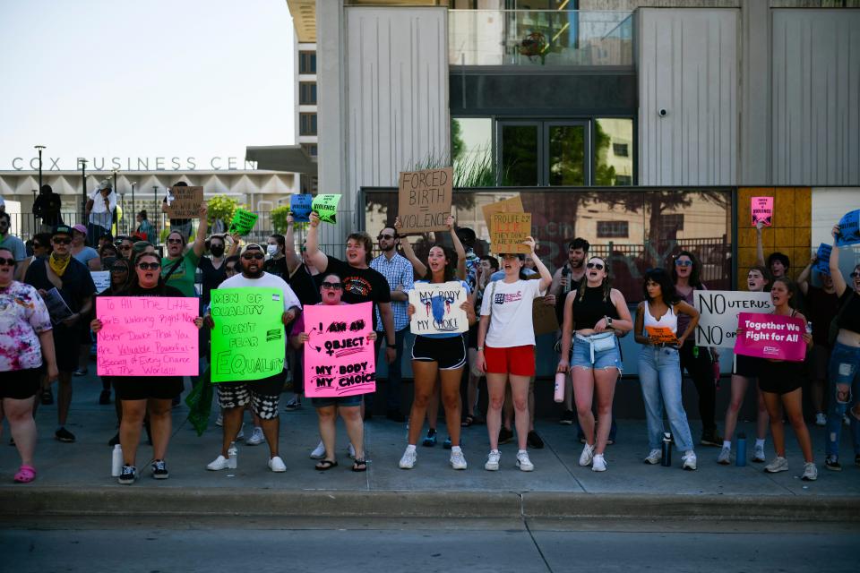 A row of people hold up neon signs