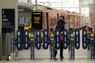 Signs requesting people keep their distance from each other are displayed on ticket barriers to help stop the spread of coronavirus in Waterloo station, London, Thursday, June 4, 2020. Waterloo station, which is widely recognised as the busiest train station in Britain, is still much quieter than normal as most commuters are still working from home and not travelling into central London offices. (AP Photo/Matt Dunham)