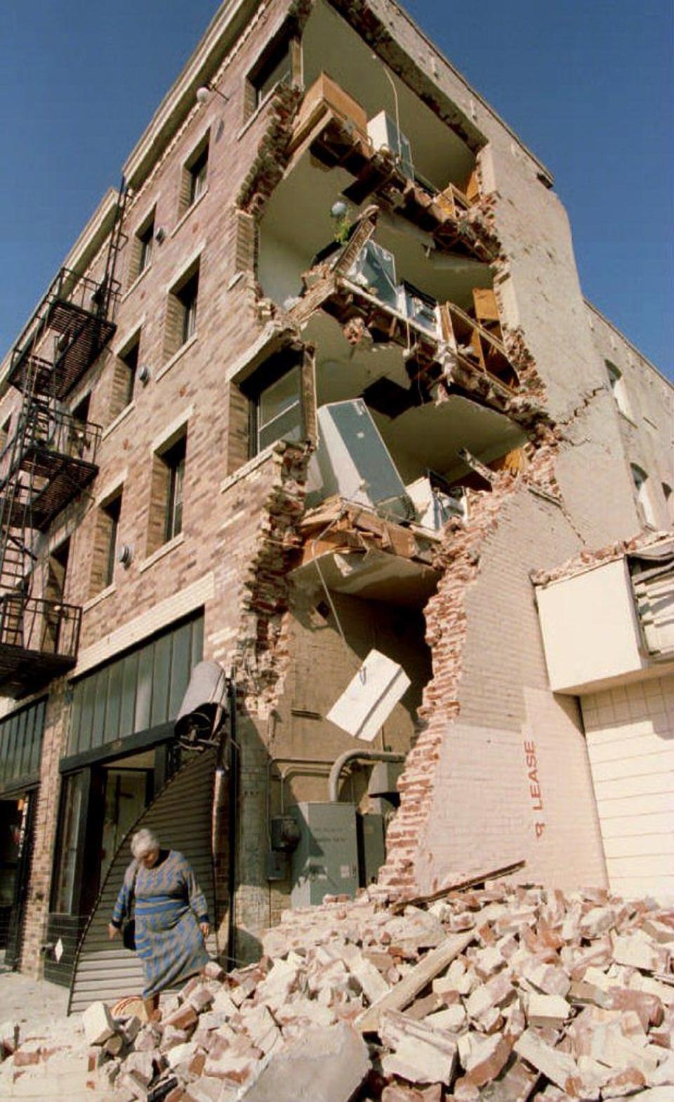 Aykui Alaverdyan walks over rubble after taking some of her belongings from her Hollywood Boulevard apartment building in Hollywood, CA, 20 January 1994, which was destroyed in the Northridge earthquake (AFP via Getty Images)