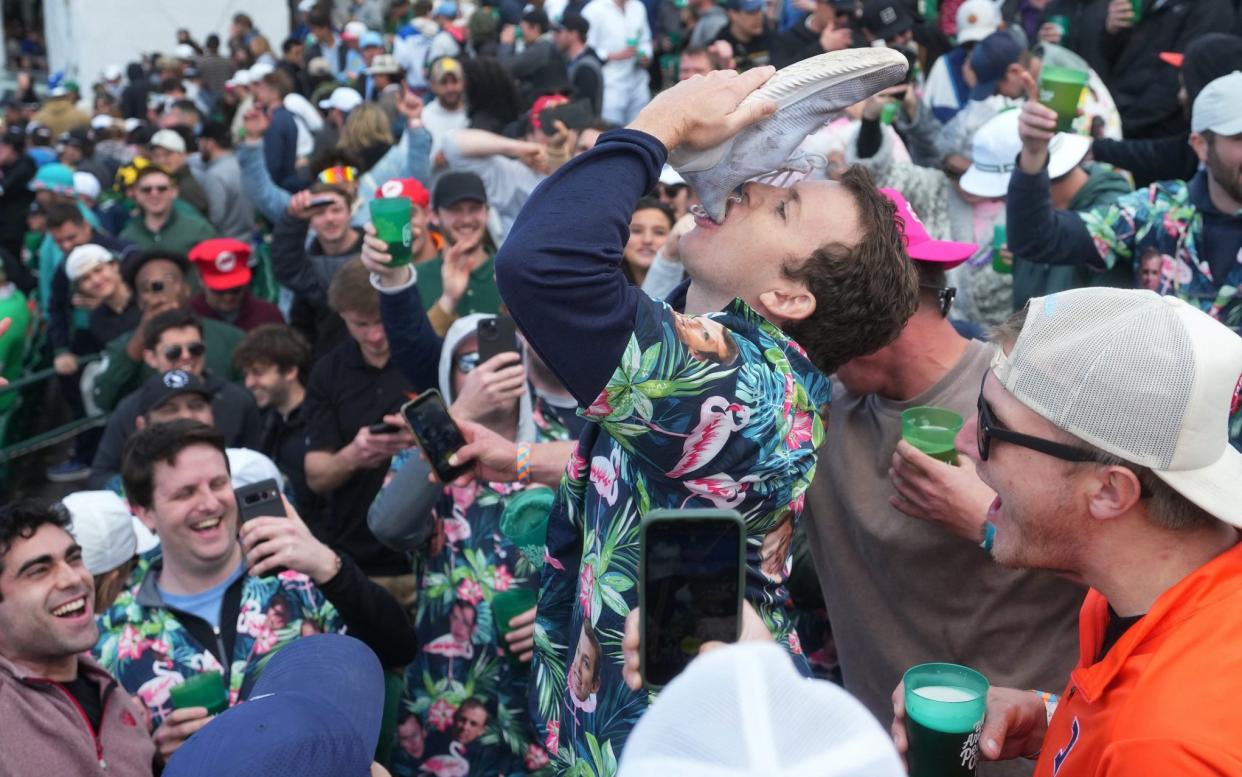 A fan drinks from a shoe in the crowd at the Phoenix Open