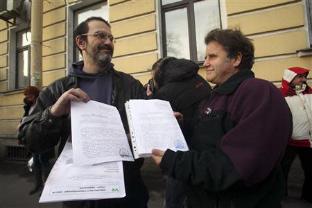 Greenpeace activist Dimitri Litvinov (L) and Peter Willcox, captain of the Greenpeace ship Arctic Sunrise, show papers certifying the termination of prosecution after they walked out of the offices of the Federal Migration Service Department in St. Petersburg, December 25, 2013. REUTERS/Stringer