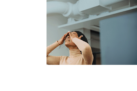 Frustrated female computer programmer with head in hands sitting in creative office