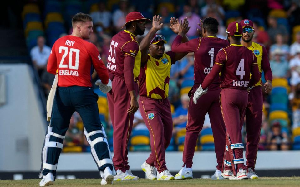 Jason Roy (L), of England, walks off the field, dismissed by Sheldon Cottrell (3R), as Kieron Pollard (2L) and Odean Smith (3L) of West Indies celebrate during the first T20I between West Indies and England at Kensington Oval  - AFP