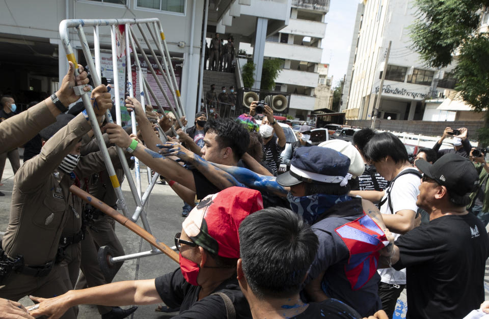 Anti-government protesters push a metal barrier into inside of the Samranrat police station in Bangkok, Thailand, Friday, Aug, 28, 2020. The protesters tussled with police on Friday as 15 of their movement leaders turned up at a police station to answer a summons linked to demonstrations denouncing the arrests. (AP Photo/Sakchai Lalit)