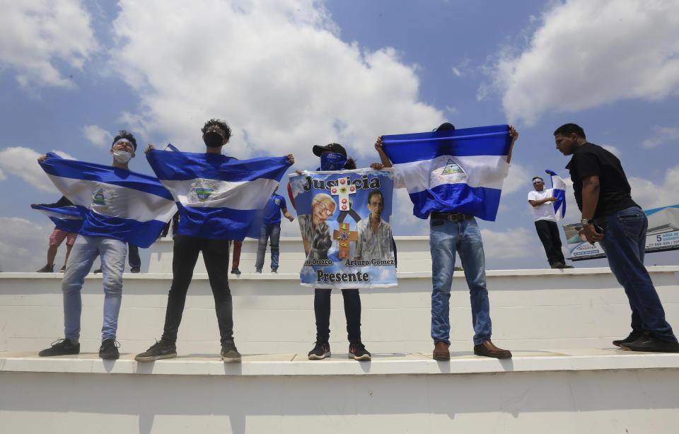 Anti-government protesters hold up flags and signs demanding the release of political prisoners on the sidelines of a Stations of the Cross procession on Good Friday in Managua, Nicaragua, Friday, April 19, 2019. Good Friday religious processions in Nicaragua’s capital have taken a decidedly political tone as people have seized on a rare opportunity to renew protests against the government of President Daniel Ortega. (AP Photo/Alfredo Zuniga)