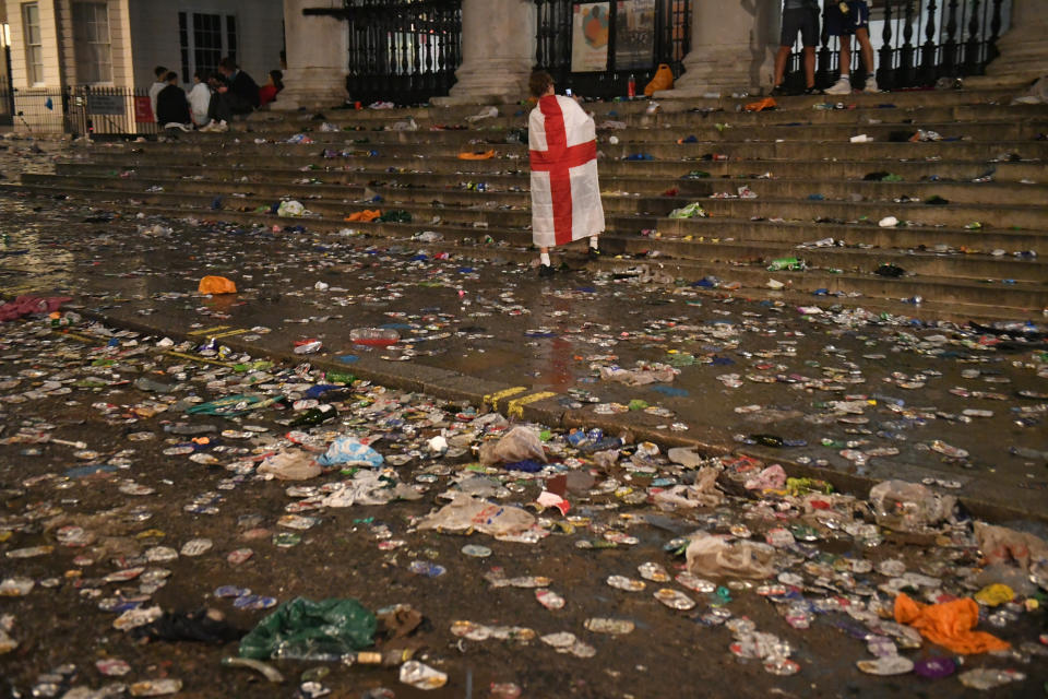 An England fan draped in a flag walks amongst the litter strewn on the ground in front of St Martin-In-The-Fields church, in Trafalgar Square, London, after Italy beat England on penalties to win the UEFA Euro 2020 Final. Picture date: Sunday July 11, 2021.