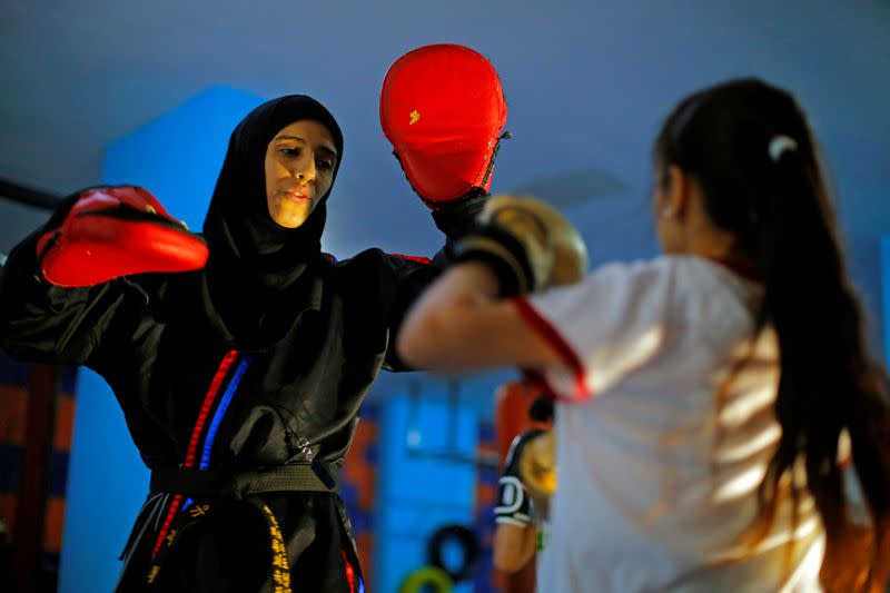 La entrenadora de artes marciales Seham Amer practica movimientos de defensa personal con una estudiante en un gimnasio en Saná