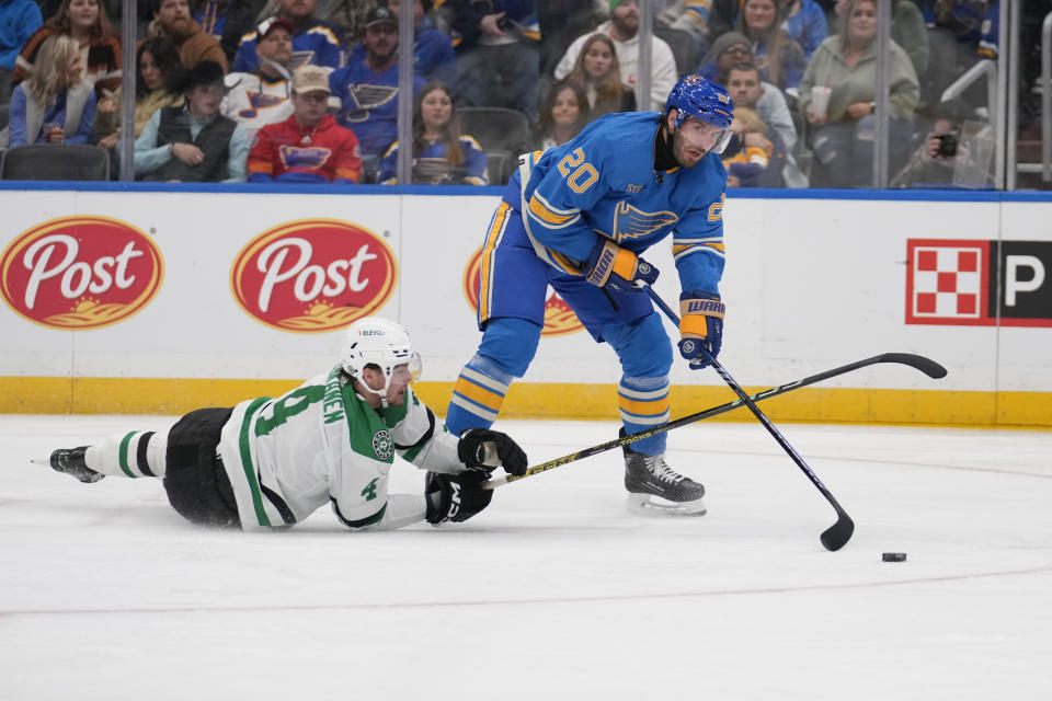 St. Louis Blues' Brandon Saad (20) passes as Dallas Stars' Miro Heiskanen (4) defends during the second period of an NHL hockey game Saturday, Dec. 16, 2023, in St. Louis. (AP Photo/Jeff Roberson)