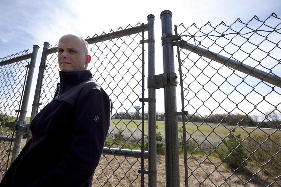 In this April 19, 2012, photo, Mike McCarthy, of Walpole, Mass., stands near a chain link fence in Foxborough, Mass., that runs along the edge a parking lot that could become the site of a proposed gambling casino. McCarthy's property in Walpole, and the Walpole town line, are about 15 feet from the fence, and McCarthy, who has two young children, worries about the impact a casino would have so close to his home. (AP Photo/Steven Senne)