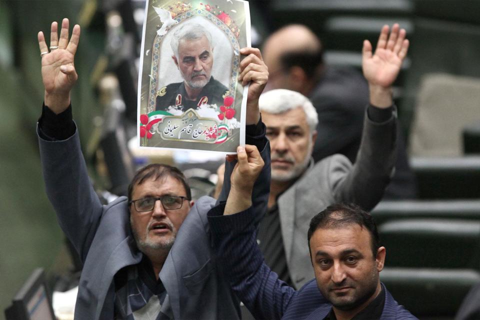 Iranian lawmakers holding pictures of slain top general Qasem Soleimani as they vote during a parliamentary session in Tehran on Jan. 7, 2020. - Iran's parliament passed a bill designating all US forces "terrorists" over the killing of a top Iranian military commander in a US strike last week. Under the newly adopted bill, all US forces and employees of the Pentagon and affiliated organizations, agents and commanders and those who ordered the "martyrdom" of Soleimani were designated as "terrorists". (Photo: /ICANA NEWS AGENCY /AFP via Getty Images)