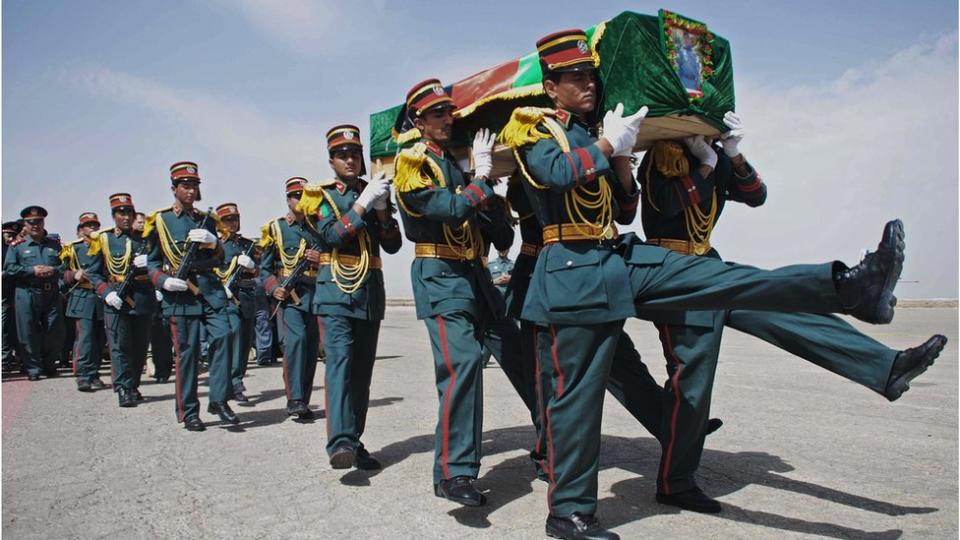 Una guardia de honor afgana carga el ataúd de un policía