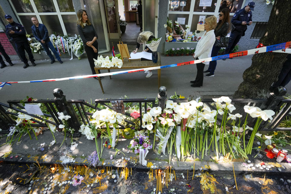 A girl signs the book of condolences in front of the Vladimir Ribnikar school, two days after a 13-year-old boy used his father's guns to kill eight fellow students and a guard, in Belgrade, Serbia, Friday, May 5, 2023. The bloodshed sent shockwaves through a Balkan nation scarred by wars, but unused to mass murders. (AP Photo/Darko Vojinovic)