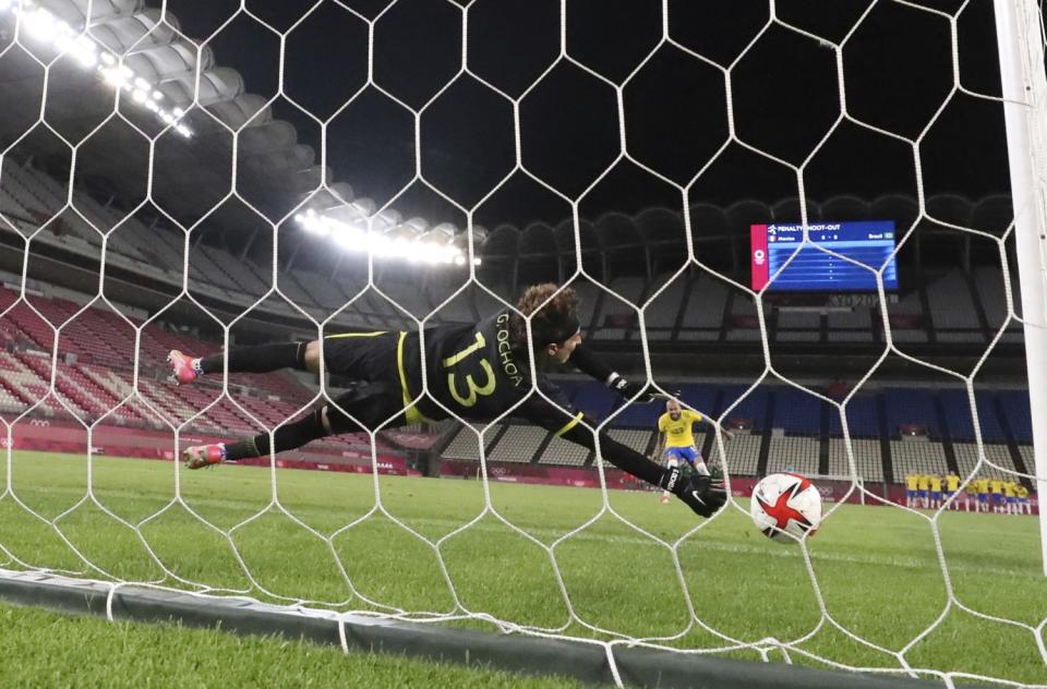 Mexico goalkeeper Guillermo Ochoa dives to his right but is unable to stop a penalty kick by Brazil's Dani Alves.