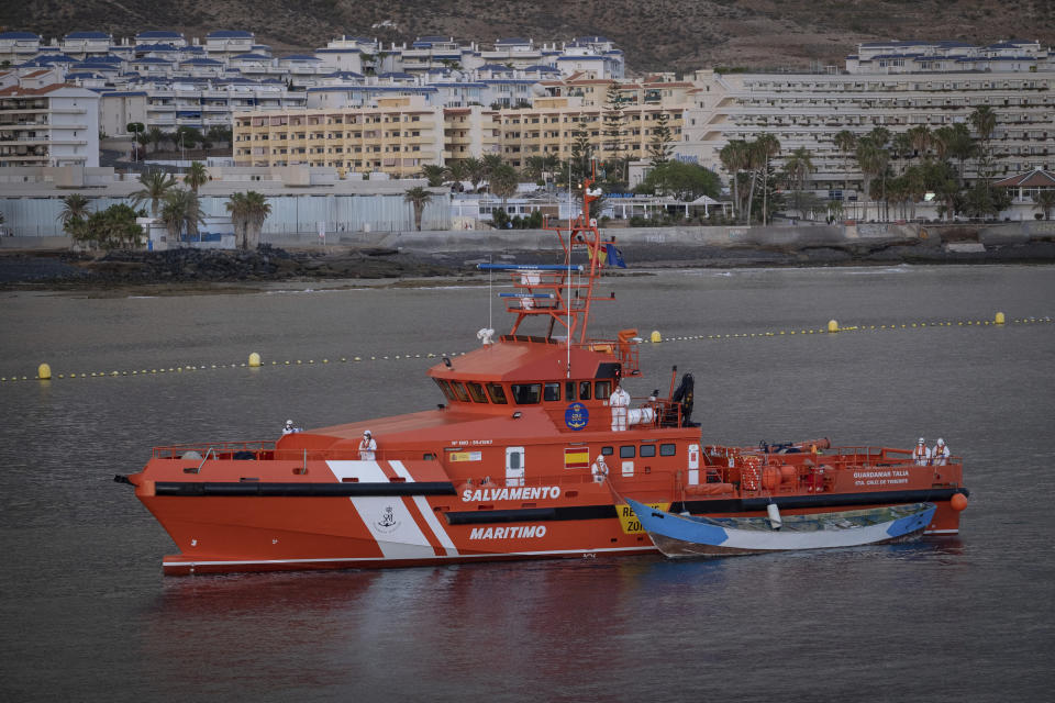 A wooden boat is towed by a Spanish Maritime Rescue Service ship as they arrive at the port of Los Cristianos in the south of Tenerife, in the Canary Island, Spain, Wednesday, April 28, 2021. Spanish authorities have brought to shore the bodies of 24 migrants from sub-Saharan Africa, among them two minors. The migrant boat was spotted on Monday by a Spanish military plane 265 nautical miles from the island of El Hierro, three survivors were airlifted, the others are believed to have died from thirst and hunger during the perilous migratory journey from the West coast of Africa to the Canary Islands. (AP Photo/Andres Gutierrez)