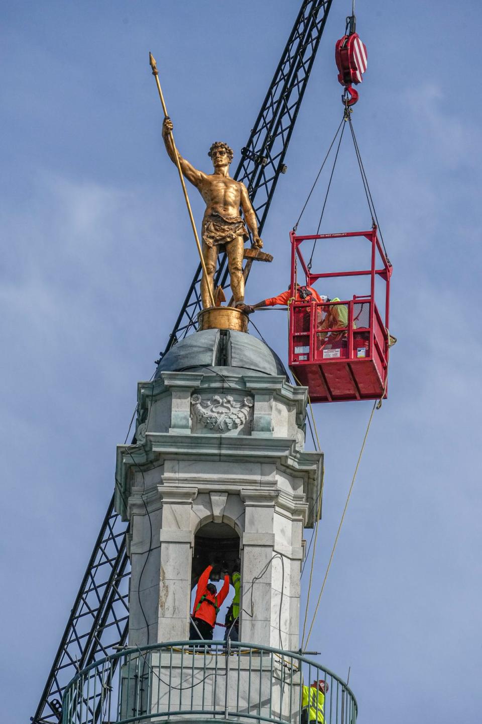 Workers secure the Independent Man last month in preparation for his removal for repairs later this fall.