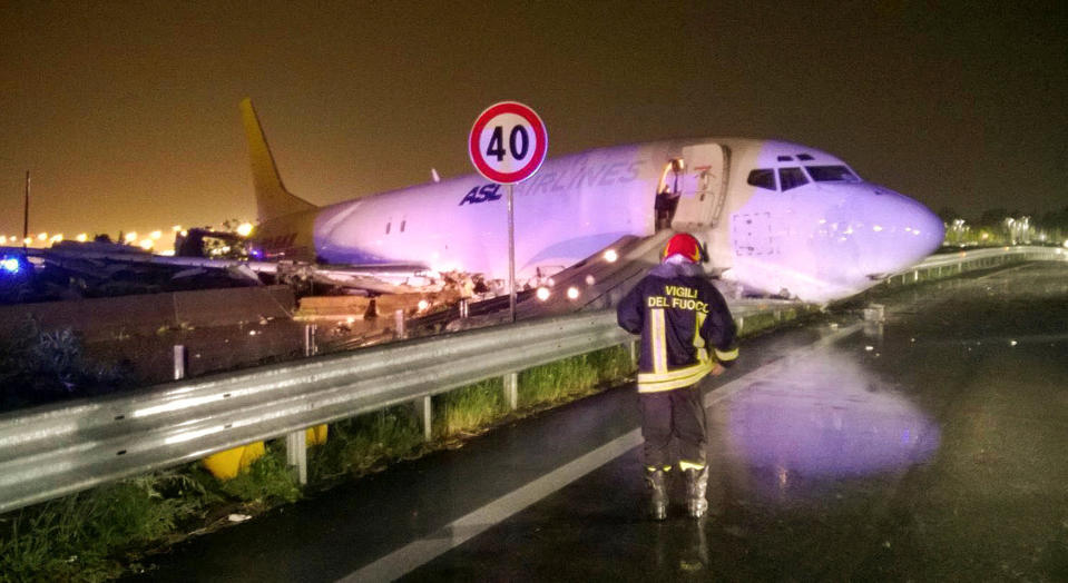 A firefighter stands in front of a cargo plane that exited the runway