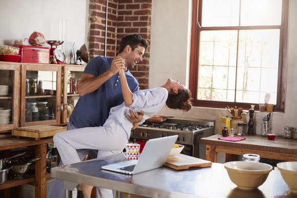 A smiling man and woman dancing in their kitchen