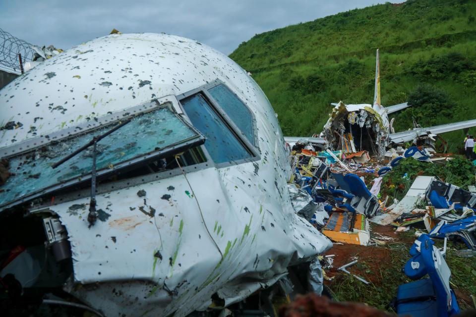 Officials inspect the wreckage of an Air India Express jet at Calicut International Airport in Karipur, Kerala, on August 8, 2020. - Fierce rain and winds lashed a plane carrying 190 people before it crash-landed and tore in two at an airport in southern India, killing at least 18 people and injuring scores more, officials said on August 8. (Photo by Arunchandra BOSE / AFP) (Photo by ARUNCHANDRA BOSE/AFP via Getty Images)