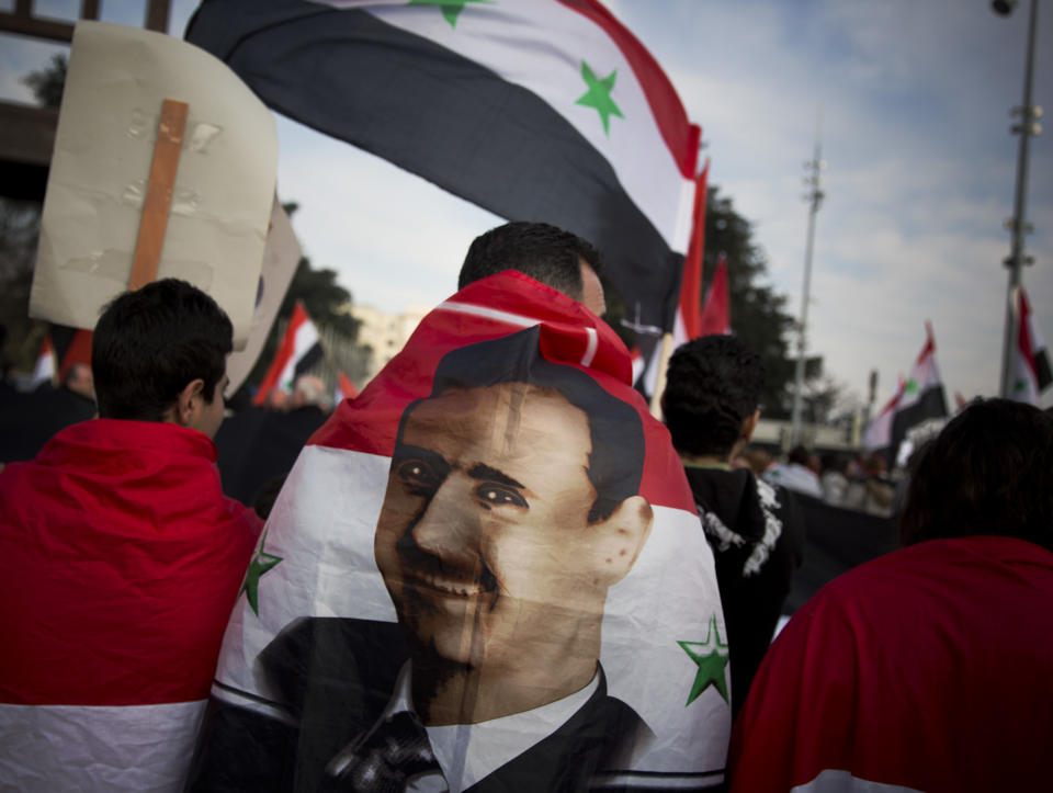 A Syrian demonstrator is wrapped in a Syrian flag carrying the picture of President Assad as they shout pro-government slogans during a demonstration outside the United Nations headquarters in Geneva, Switzerland, Friday Jan. 31, 2014. The first face-to-face meetings between Syria’s warring sides in three years were wrapping up Friday, with a patient U.N. mediator struggling to build enough momentum for a more constructive second round to break through the deadly impasse. (AP Photo/Anja Niedringhaus)