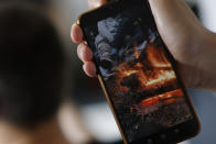 A refugee from Syria ,who came to Europe from Belarus border, shows a photo on a mobile phone picturing a fireplace in a forest as he said was taken during his travel between Belarus and Poland during an interview with The Associated Press in Berlin, Germany, Monday, June 27, 2022. (AP Photo/Michele Tantussi)