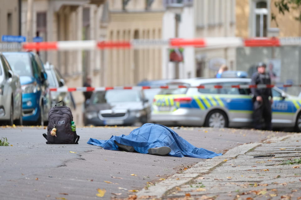 A body lies on a road in Halle, Germany, Wednesday, Oct. 9, 2019 after a shooting incident. A gunman fired several shots on Wednesday in German city of Halle and at least two got killed, according to local media FOCUS online. The gunman is on the run and police have sealed off the surrounding area. (Sebastian Willnow/dpa via AP)