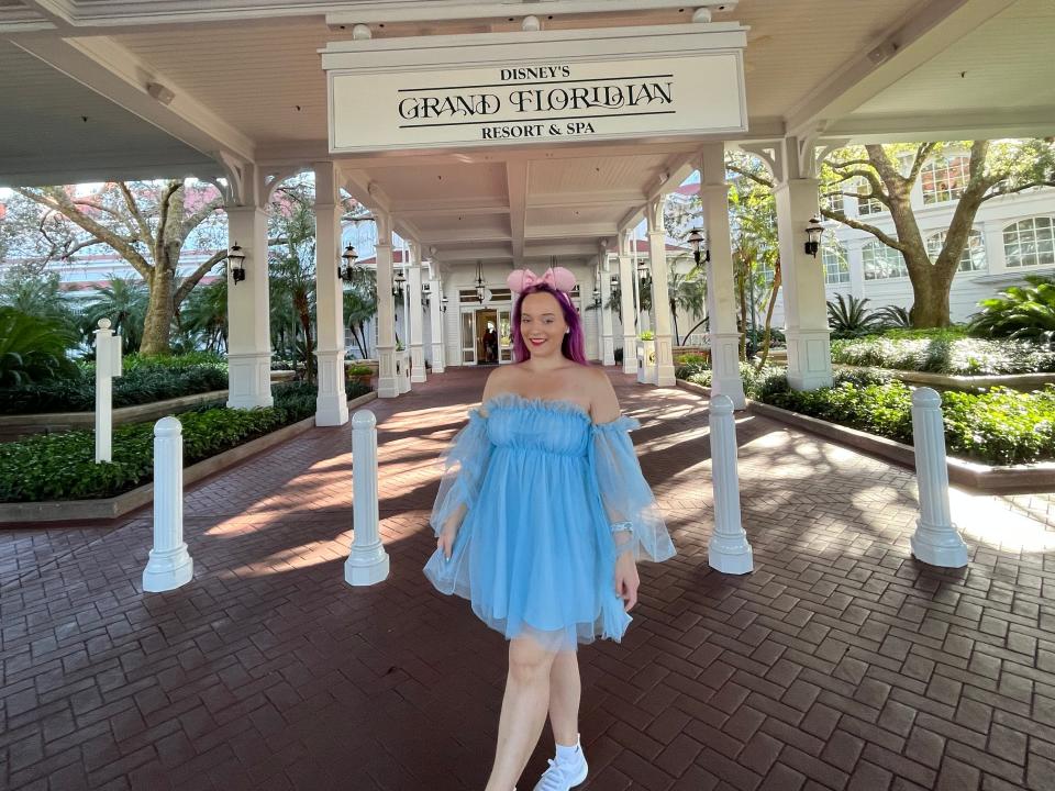 jenna posing for a photo under the sign for disney's grand floridian resort at the main entrance