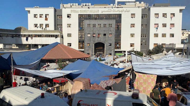 People, including Palestinian children, who fled their house due to Israeli strikes, gather at Al Shifa hospital where they shelter