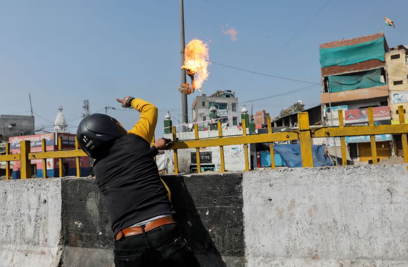 Un hombre que apoya una nueva ley de ciudadanía lanza una cóctel molotov a un santuario musulmán durante un enfrentamiento con los que se oponen a la ley en Nueva Delhi