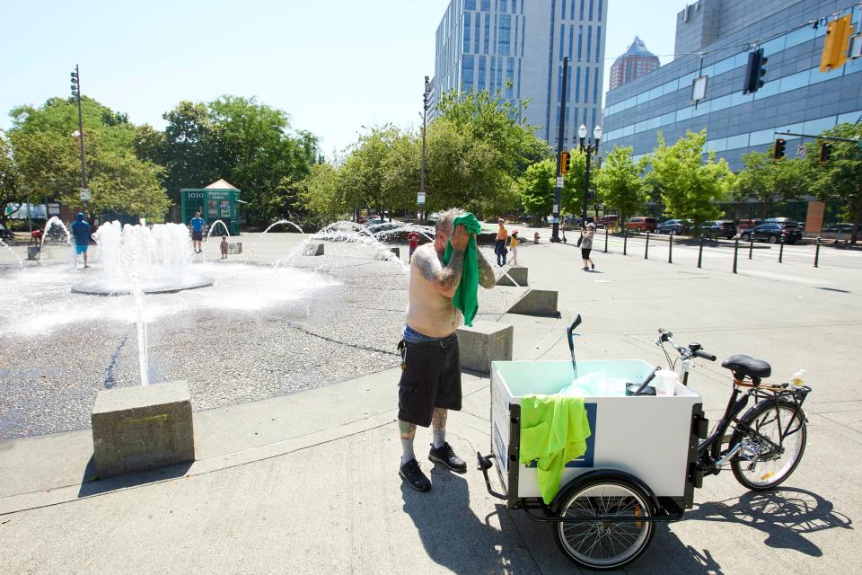 Man cools himself off with a towel near a fountain in Oregon.