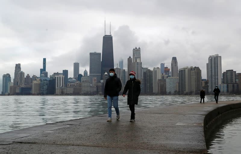 People wearing protective face masks walk, as the global outbreak of the coronavirus disease (COVID-19) continues, along the shores of Lake Michigan in Chicago, Illinois