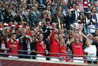 Arsenal's manager Arsene Wenger (R) looks at his players holding the trophy after winning the English FA Cup final match against Hull City at Wembly Stadium in London on May 17, 2014