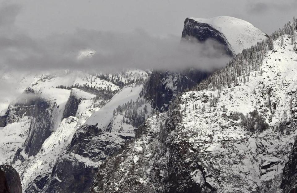 A cloud partially obscures Half Dome, top right, with Cloud’s Rest to the left as the higher elevations around Yosemite Valley still show snow from its last snowfall, photographed Friday, Feb 9, 2024 in Yosemite National Park. ERIC PAUL ZAMORA/ezamora@fresnobee.com